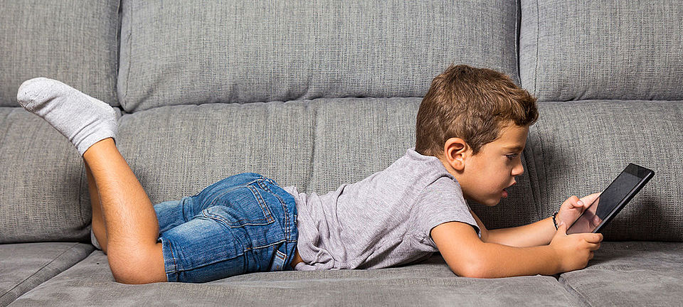 Junge mit Tablet am Sofa