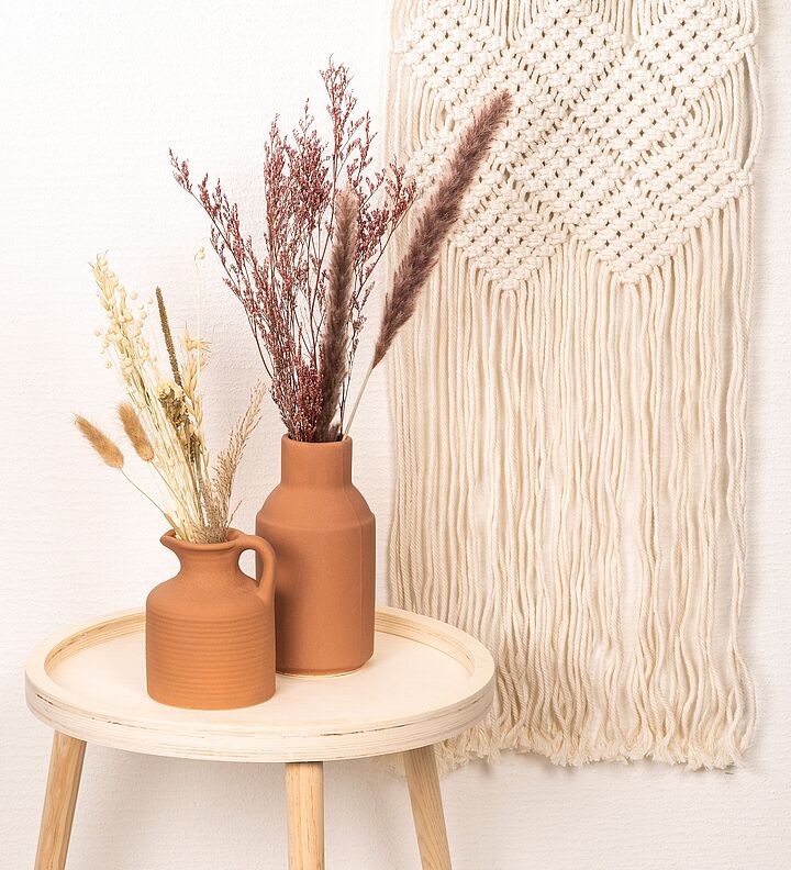 Must-haves für die Frühlingszeit Terracotta-Krüge auf Tisch mit Makramee-Behang