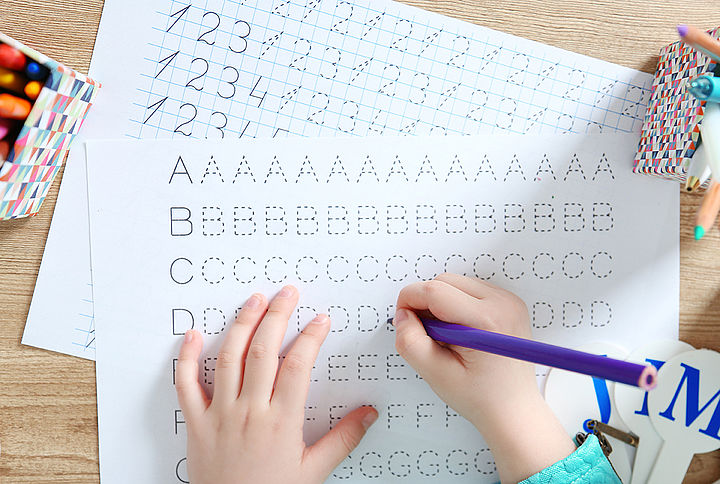 Schreibübungen zum Nachziehen Kind zieht Buchstaben mit Buntstift nach